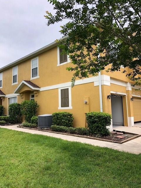 A two-story yellow stucco building with a sidewalk and landscaping in the foreground — 10923 DERRINGER DRIVE, ORLANDO, FL