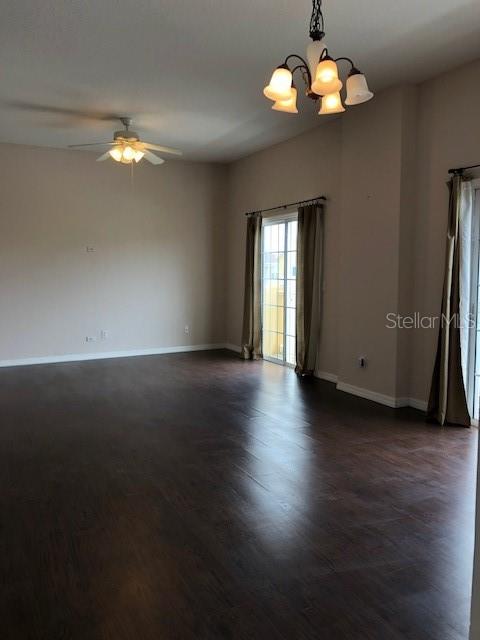 A spacious living room features dark wood flooring, a ceiling fan, and a chandelier — 10923 DERRINGER DRIVE, ORLANDO, FL