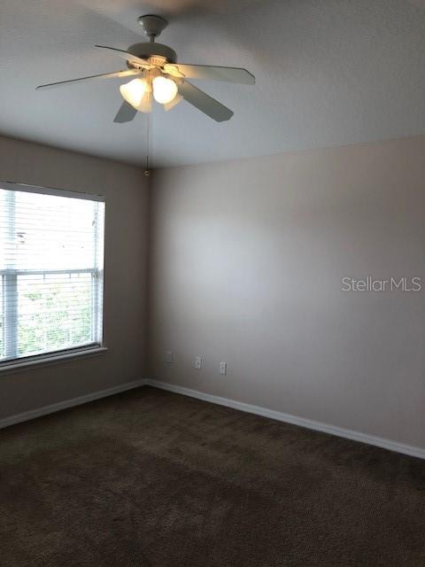 An empty bedroom features beige walls, brown carpeting, a window with blinds, and a ceiling fan — 10923 DERRINGER DRIVE, ORLANDO, FL