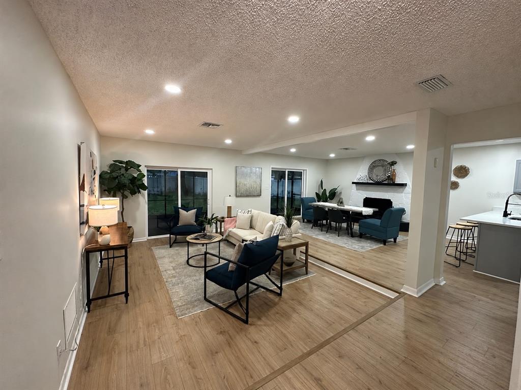 An open-concept living and dining area features light wood flooring, recessed lighting, and a fireplace — 22360 STILLWOOD DRIVE, LAND O LAKES, FL