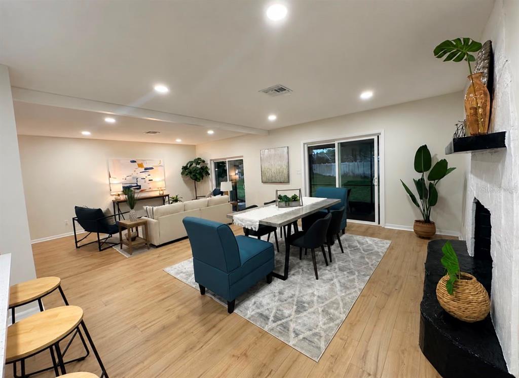 An open-concept living and dining area features light wood floors, recessed lighting, and sliding doors — 22360 STILLWOOD DRIVE, LAND O LAKES, FL