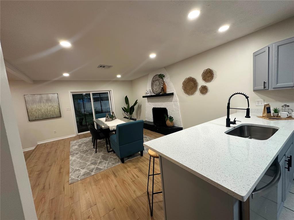 A kitchen island with a sink overlooks a dining area featuring a fireplace and rug — 22360 STILLWOOD DRIVE, LAND O LAKES, FL