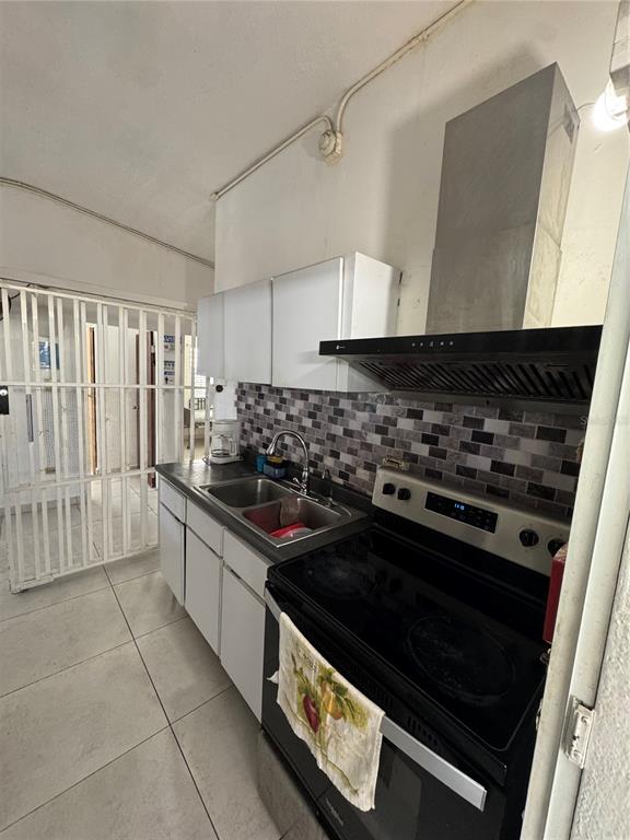 A kitchen features white cabinets, a black stove with a range hood, and tiled backsplash — N618 CALLE JULIO ANDINO, SAN JUAN, PR