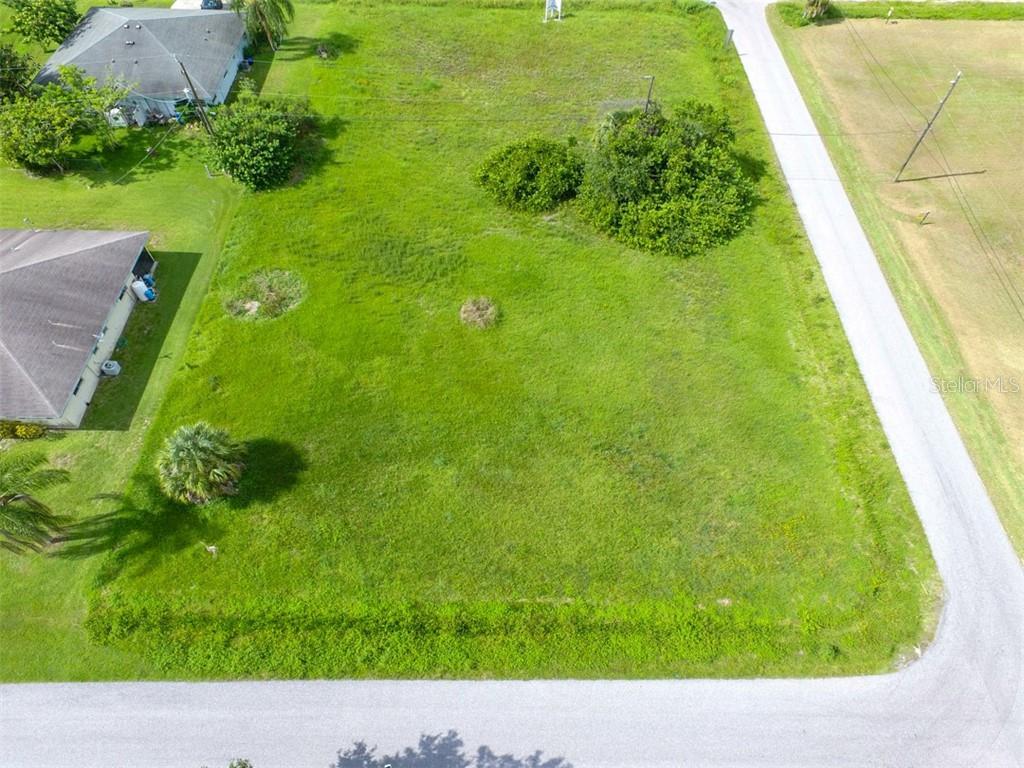 An aerial view shows a vacant, grassy rectangular lot bordered by paved roads and houses — 12000 TAMIAMI LOTS 15 & 16 TRAIL S, NORTH PORT, FL