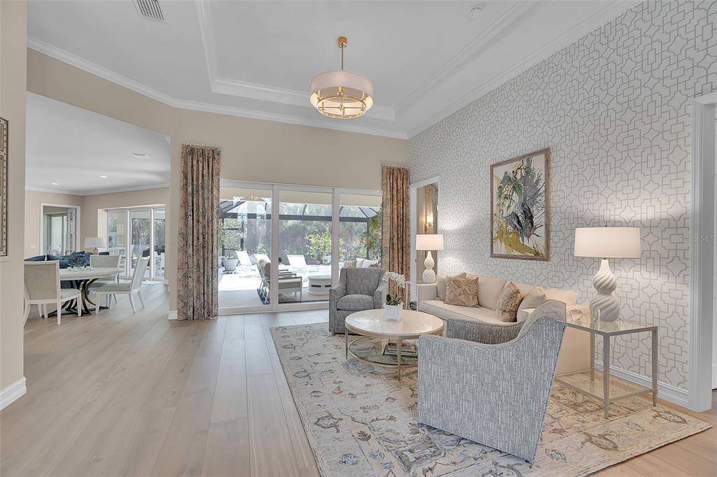 A living room with patterned wallpaper, a tray ceiling, and sliding doors to a patio — 8986 BLOOMFIELD BOULEVARD, SARASOTA, FL