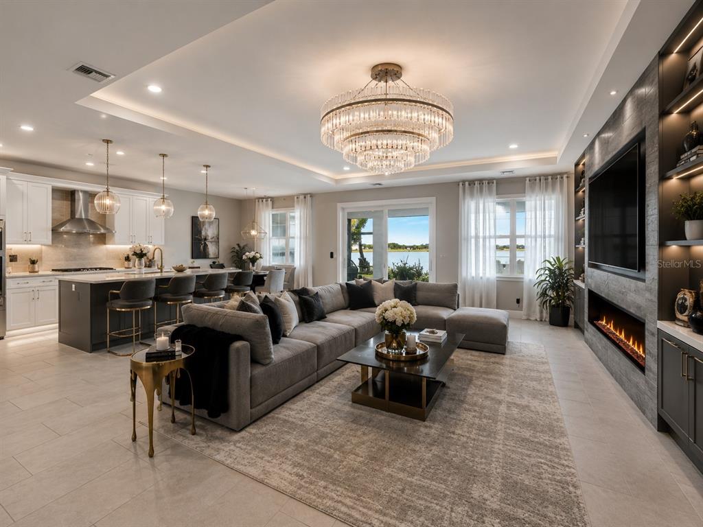 An open-concept living room and kitchen feature a large sectional, fireplace, and lake view — 16148 PRESERVATION BOULEVARD, PUNTA GORDA, FL