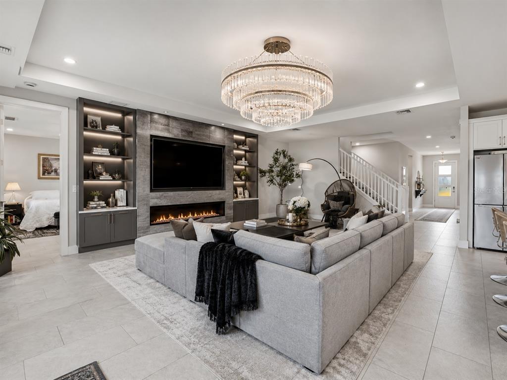 A modern living room features a large gray sectional, a stone fireplace, and a crystal chandelier — 16148 PRESERVATION BOULEVARD, PUNTA GORDA, FL