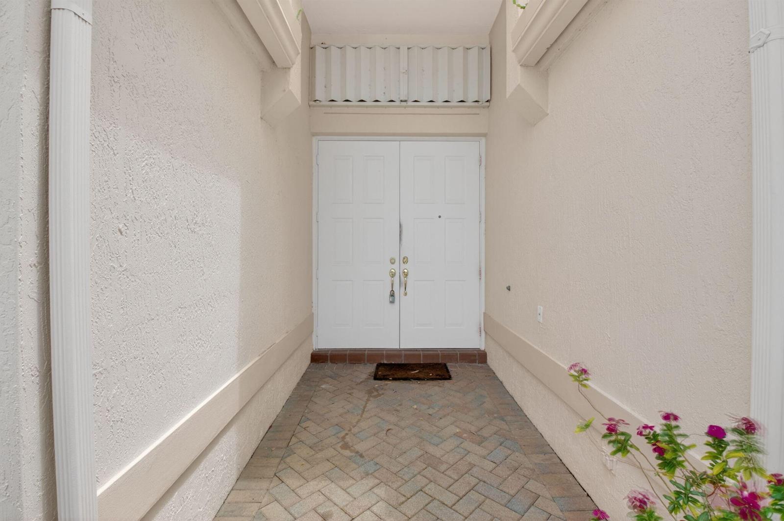 A white double door entrance features a brick paver walkway and a small plant — 5304 Wycombe Avenue, Boynton Beach FL 33437, BOYNTON BEACH, FL