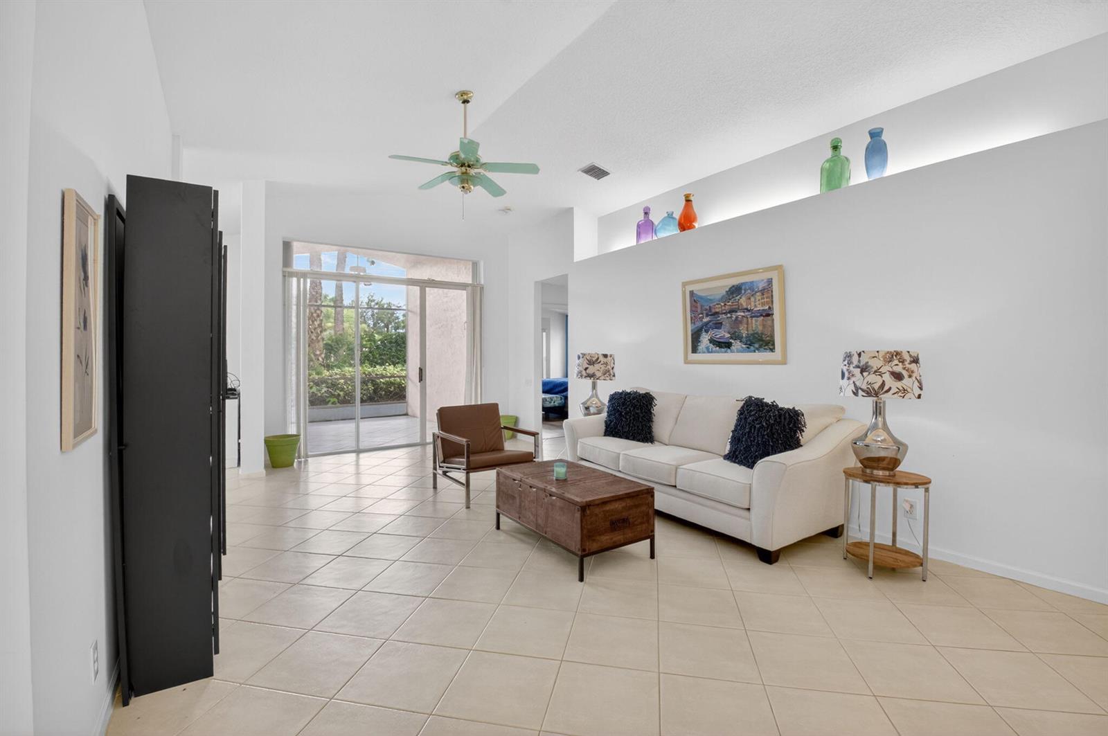 A bright living room features tile flooring, a white sofa, and a high display ledge — 5304 Wycombe Avenue, Boynton Beach FL 33437, BOYNTON BEACH, FL