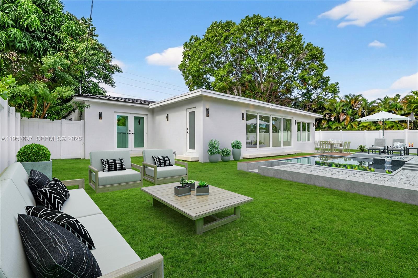 A bright living room features white modular sofas, a dark wood coffee table, and sliding doors — 1917 N Swinton Ave, Delray Beach FL 33444, DELRAY BEACH, FL