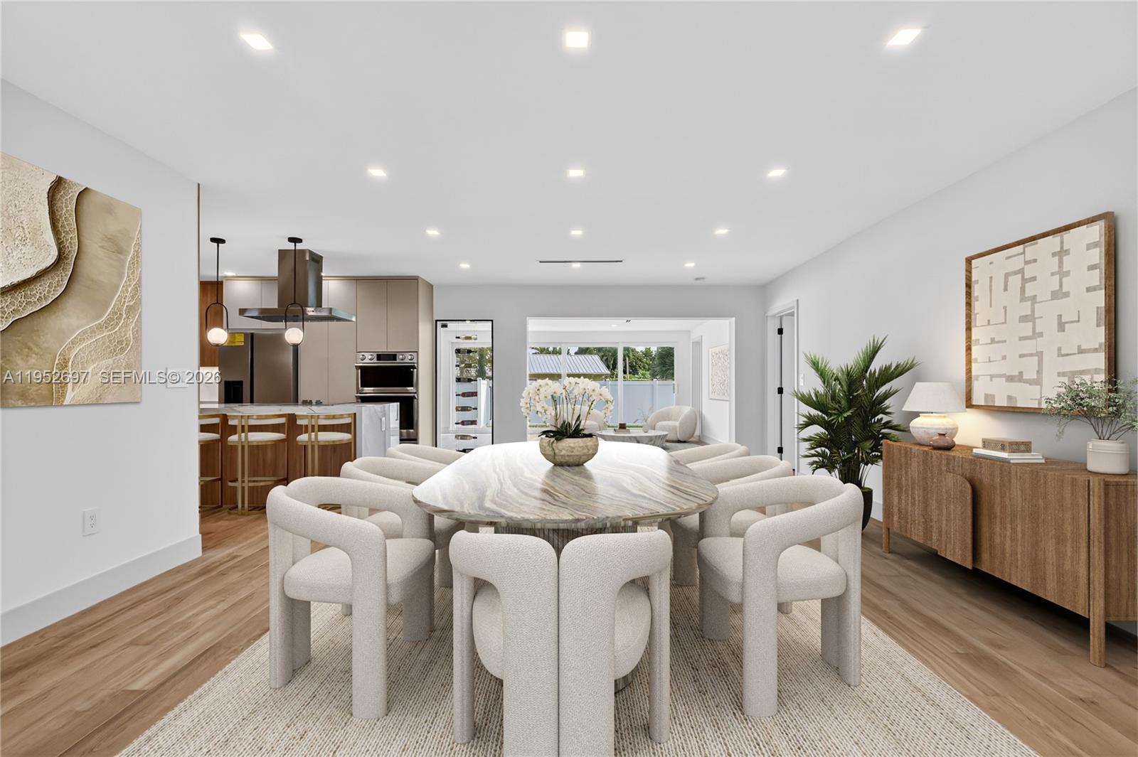 A modern open-concept dining area and kitchen feature wood-look flooring and marble-topped island — 1917 N Swinton Ave, Delray Beach FL 33444, DELRAY BEACH, FL