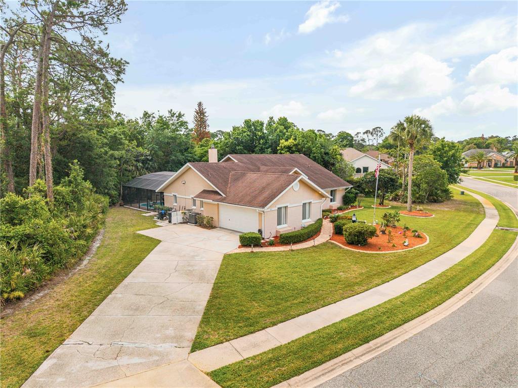 An aerial view of a single-story house with a concrete driveway and a screened pool — 107 MUIRFIELD DRIVE, DAYTONA BEACH, FL