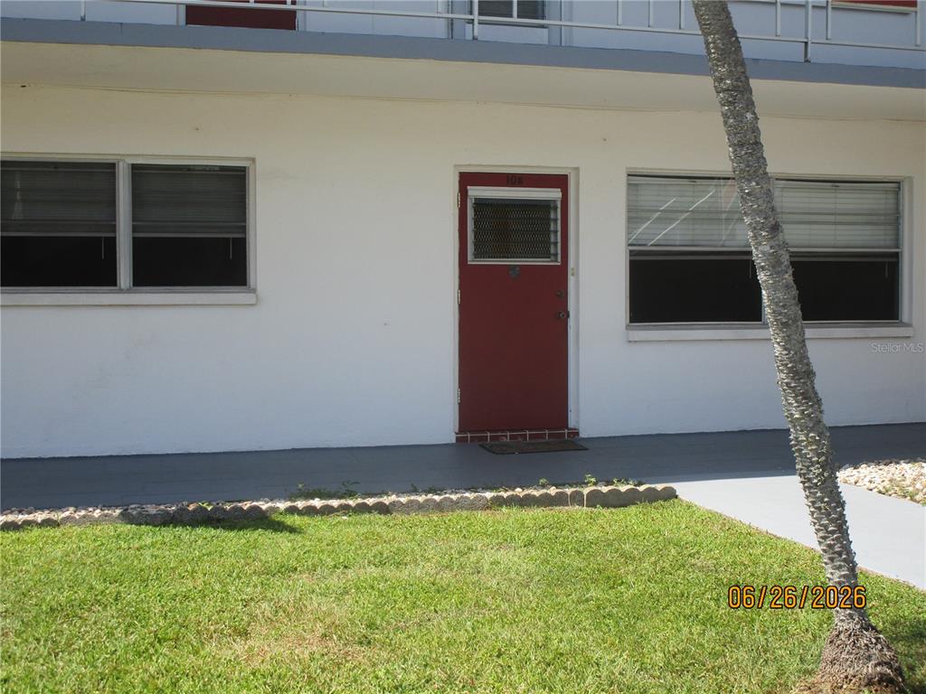A red door with a window is centered between two windows on a white building — 1950 58TH AVENUE N UNIT 10, ST PETERSBURG, FL
