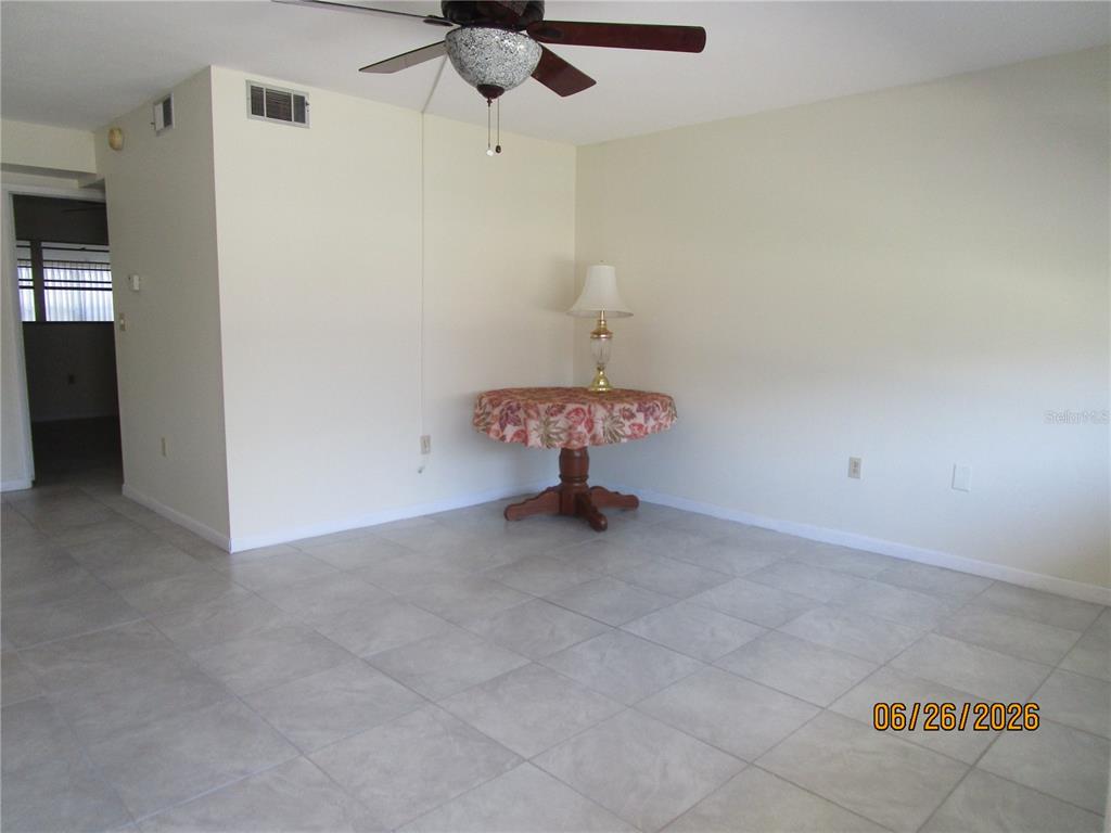 A room with light-colored tile flooring, a ceiling fan, and a small round table — 1950 58TH AVENUE N UNIT 10, ST PETERSBURG, FL
