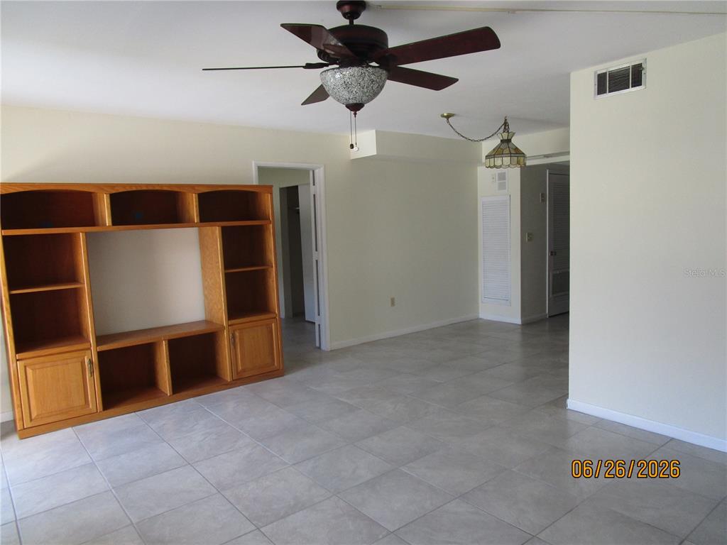 A living room features light tile flooring, a ceiling fan, and a large wooden entertainment center — 1950 58TH AVENUE N UNIT 10, ST PETERSBURG, FL