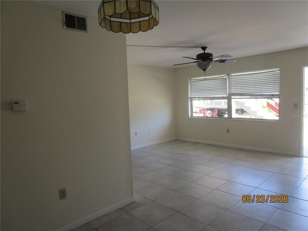 An empty room features light-colored tile flooring, a ceiling fan, and a large window — 1950 58TH AVENUE N UNIT 10, ST PETERSBURG, FL