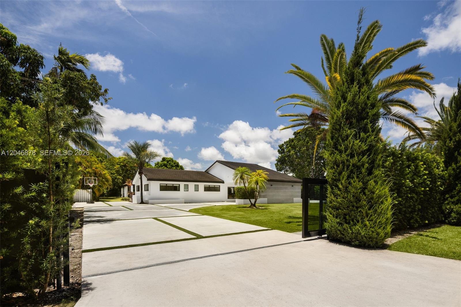 A white house with a dark roof sits behind a gated concrete driveway and lawn — 8960 SW 118th St, Miami FL 33176, MIAMI, FL