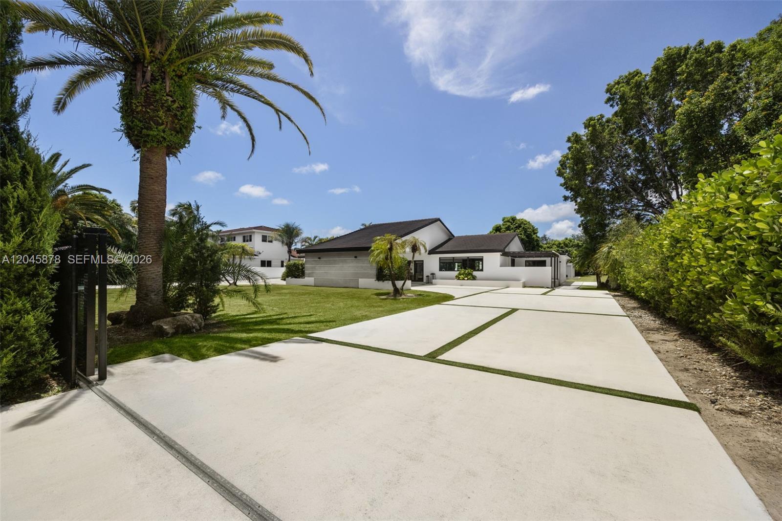 A wide concrete driveway leads to a white house with a dark roof and palm trees — 8960 SW 118th St, Miami FL 33176, MIAMI, FL