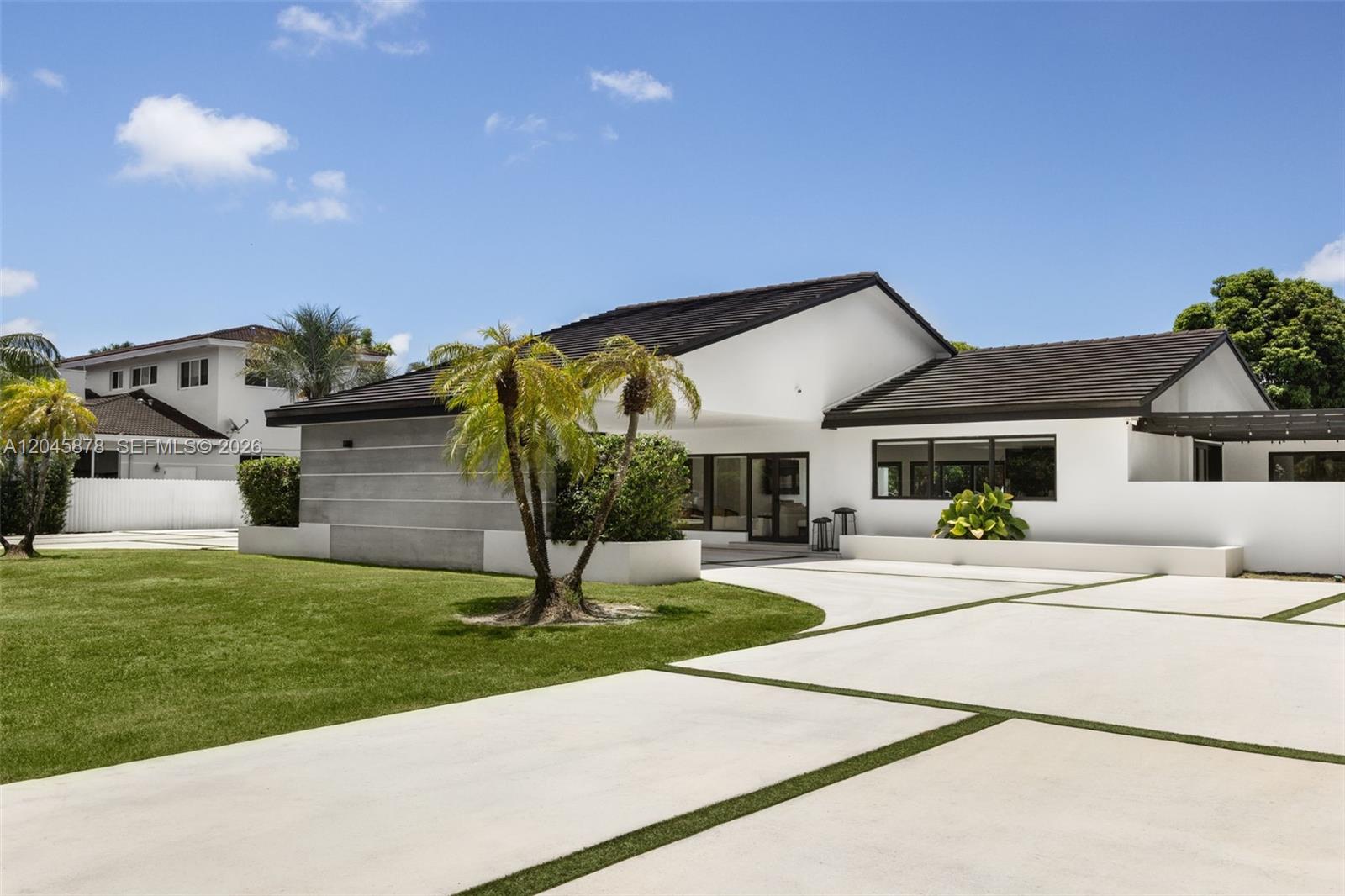 A modern white house features a dark tiled roof, concrete driveway, and palm trees — 8960 SW 118th St, Miami FL 33176, MIAMI, FL