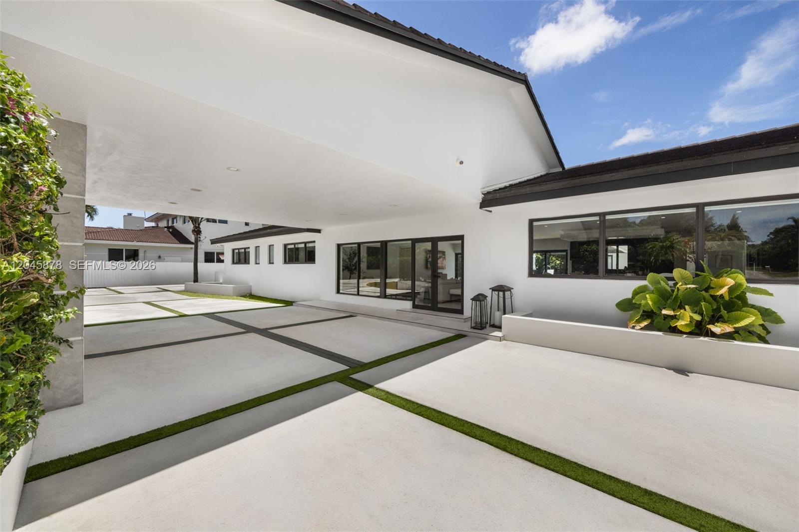 A modern home exterior features a large covered carport with concrete pavers and grass strips — 8960 SW 118th St, Miami FL 33176, MIAMI, FL