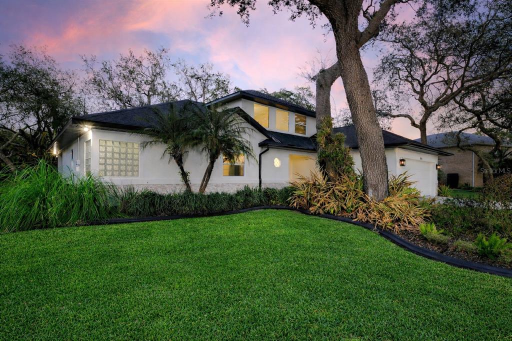 A white two-story house with a green lawn and large trees at dusk — 3311 OAK VISTA DRIVE, PORT ORANGE, FL