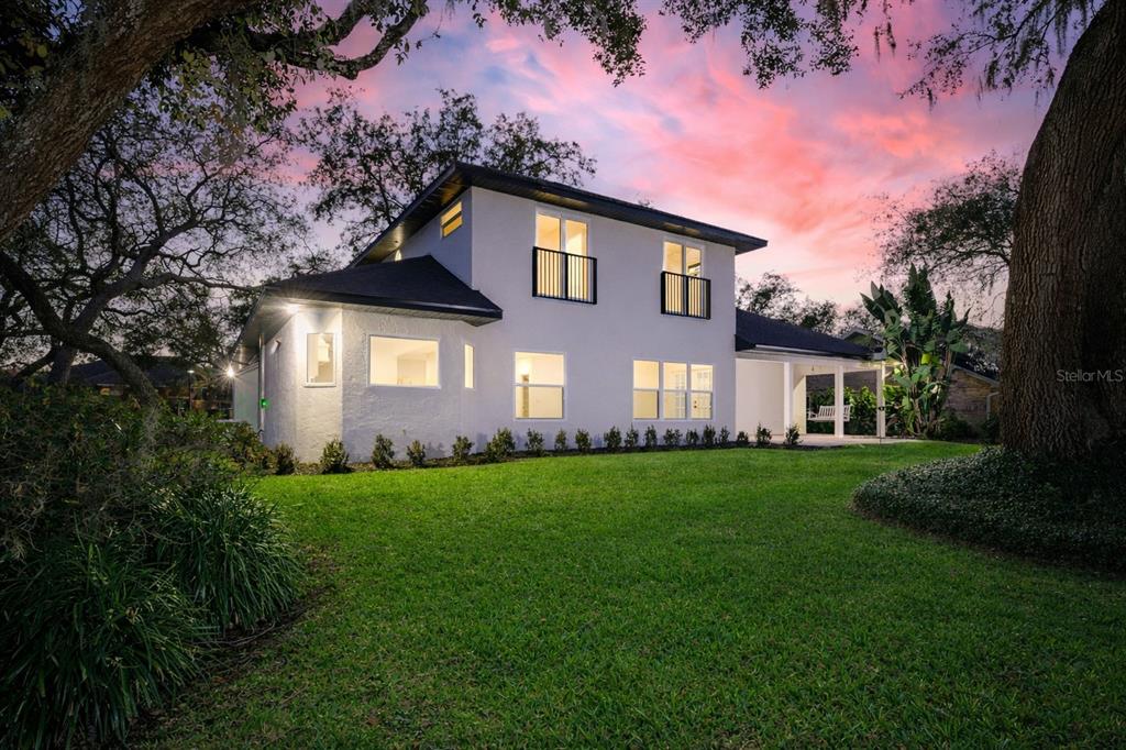 A two-story white house with a dark roof sits on a grassy lawn at dusk — 3311 OAK VISTA DRIVE, PORT ORANGE, FL