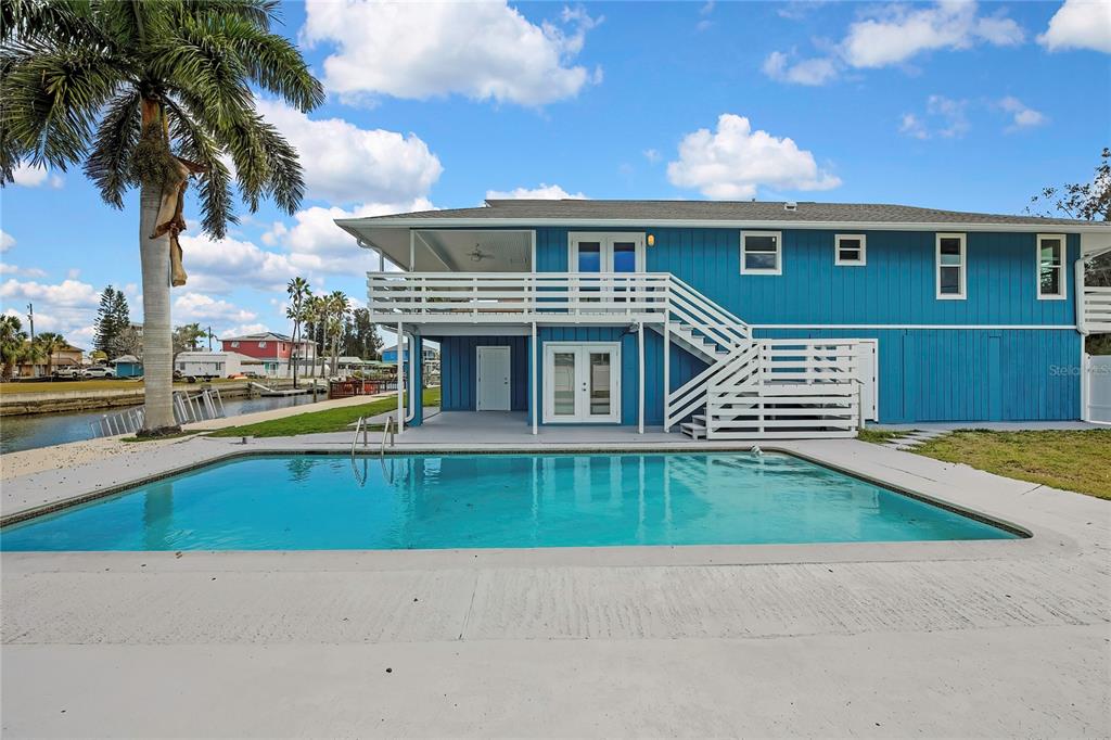 A blue two-story house with a swimming pool and a deck overlooking a canal — 6703 SEAVIEW BOULEVARD, HUDSON, FL
