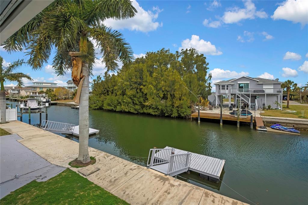 A view of a canal with docks, a palm tree, and a house across the water — 6703 SEAVIEW BOULEVARD, HUDSON, FL