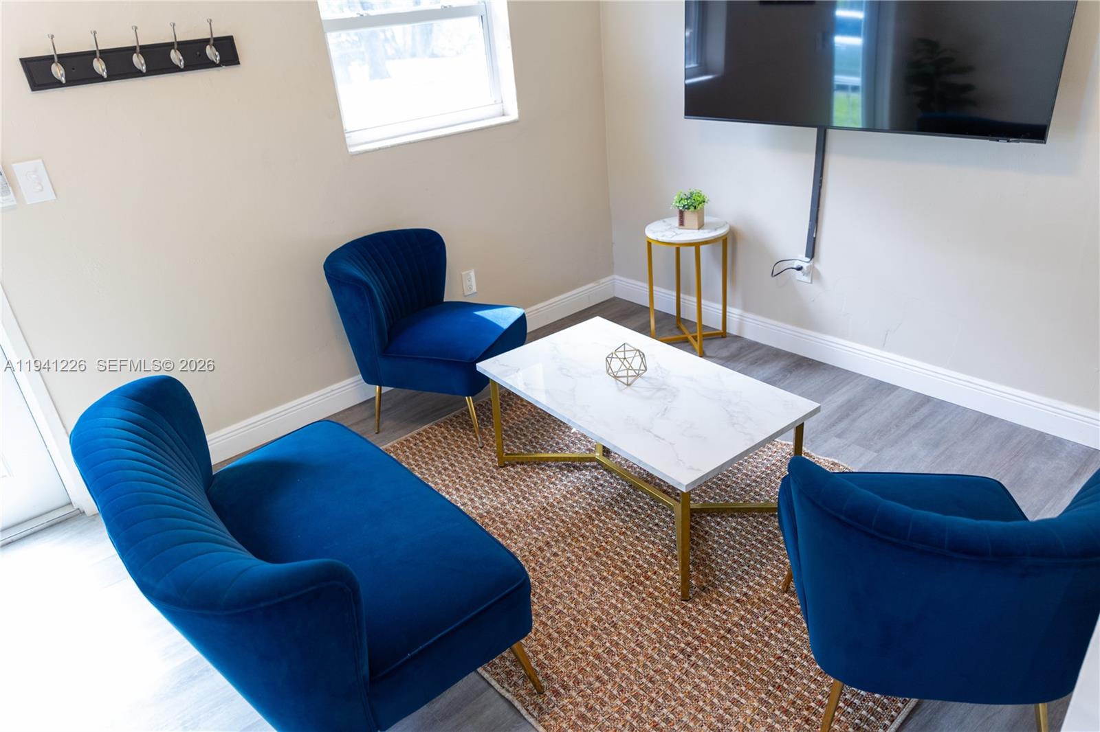 A living area features three blue velvet chairs, a marble coffee table, and a television — 250 NW 14th Way # 250, Dania Beach FL 33004, DANIA BEACH, FL
