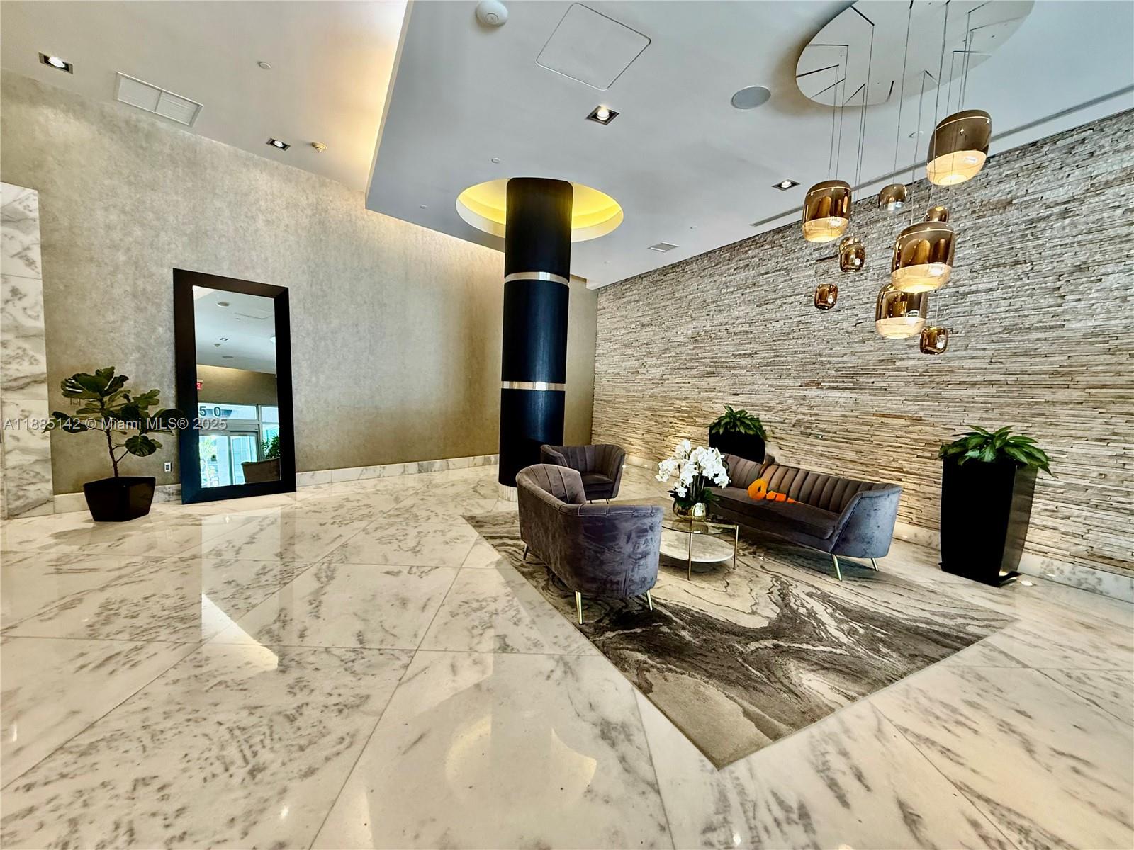 A modern lobby features a stone accent wall, marble floors, and a cluster of pendant lights — 1250 S Miami # 1603, Miami FL 33130, MIAMI, FL