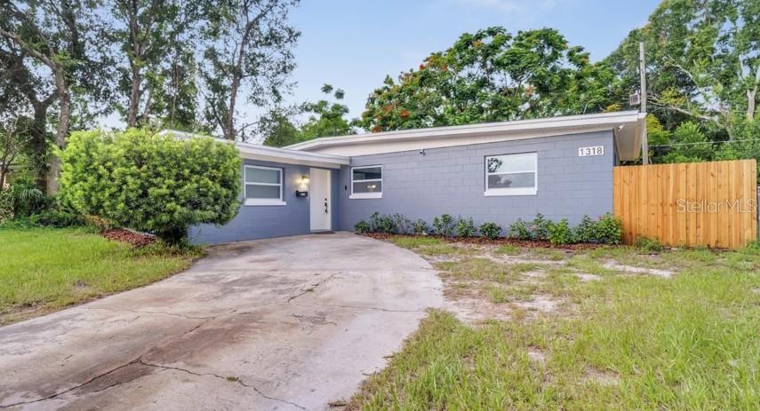 A gray concrete block house with a white front door and a wooden privacy fence — 1318 TERRE CIA AVENUE, ORLANDO, FL
