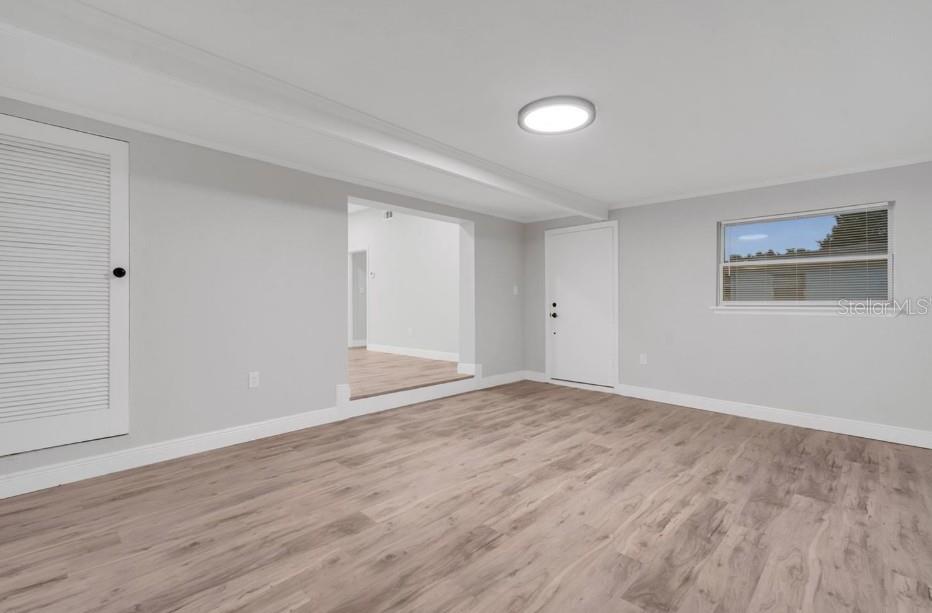 A bright room with light gray walls, wood-look flooring, a white door, and a window — 1318 TERRE CIA AVENUE, ORLANDO, FL