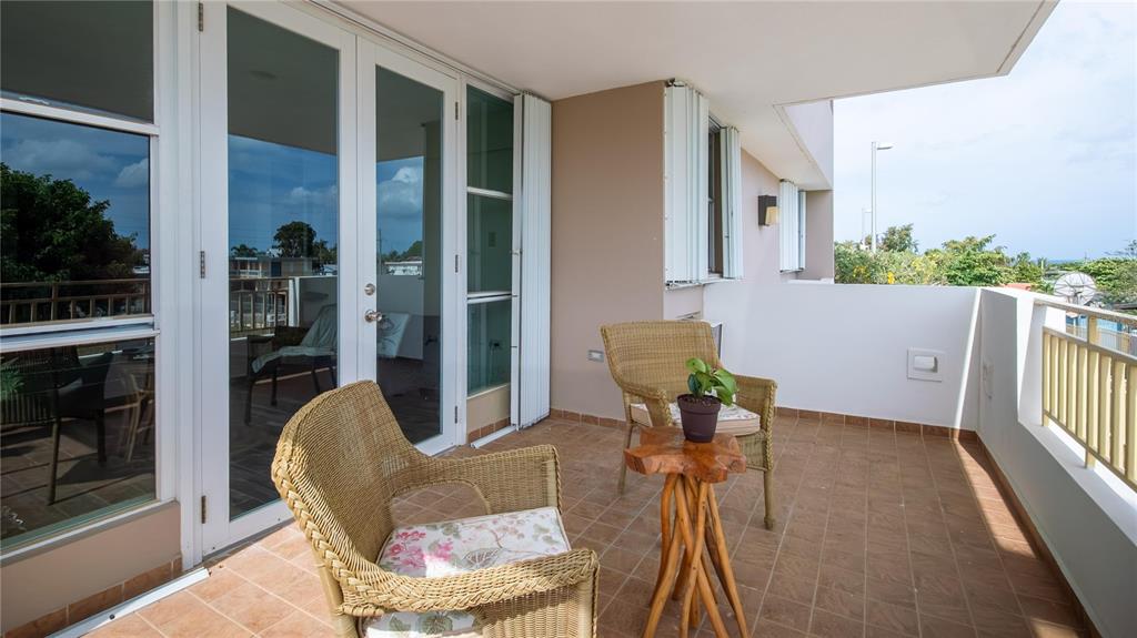 A balcony features tiled flooring, two wicker chairs, a small wooden table, and glass doors — Carretera 301 MANUEL PAGAN FERNANDEZ Apt 324, BOQUERON, PR