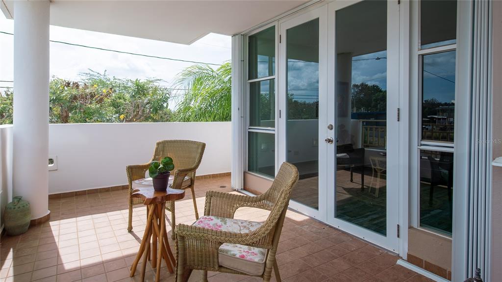 A covered balcony features tiled flooring, two wicker chairs, a small wooden table, and glass doors — Carretera 301 MANUEL PAGAN FERNANDEZ Apt 324, BOQUERON, PR