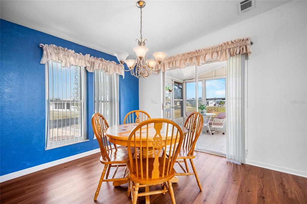 A dining room features wood-look flooring, a blue accent wall, and a sliding glass door — 9177 PINEHAVEN WAY, ENGLEWOOD, FL