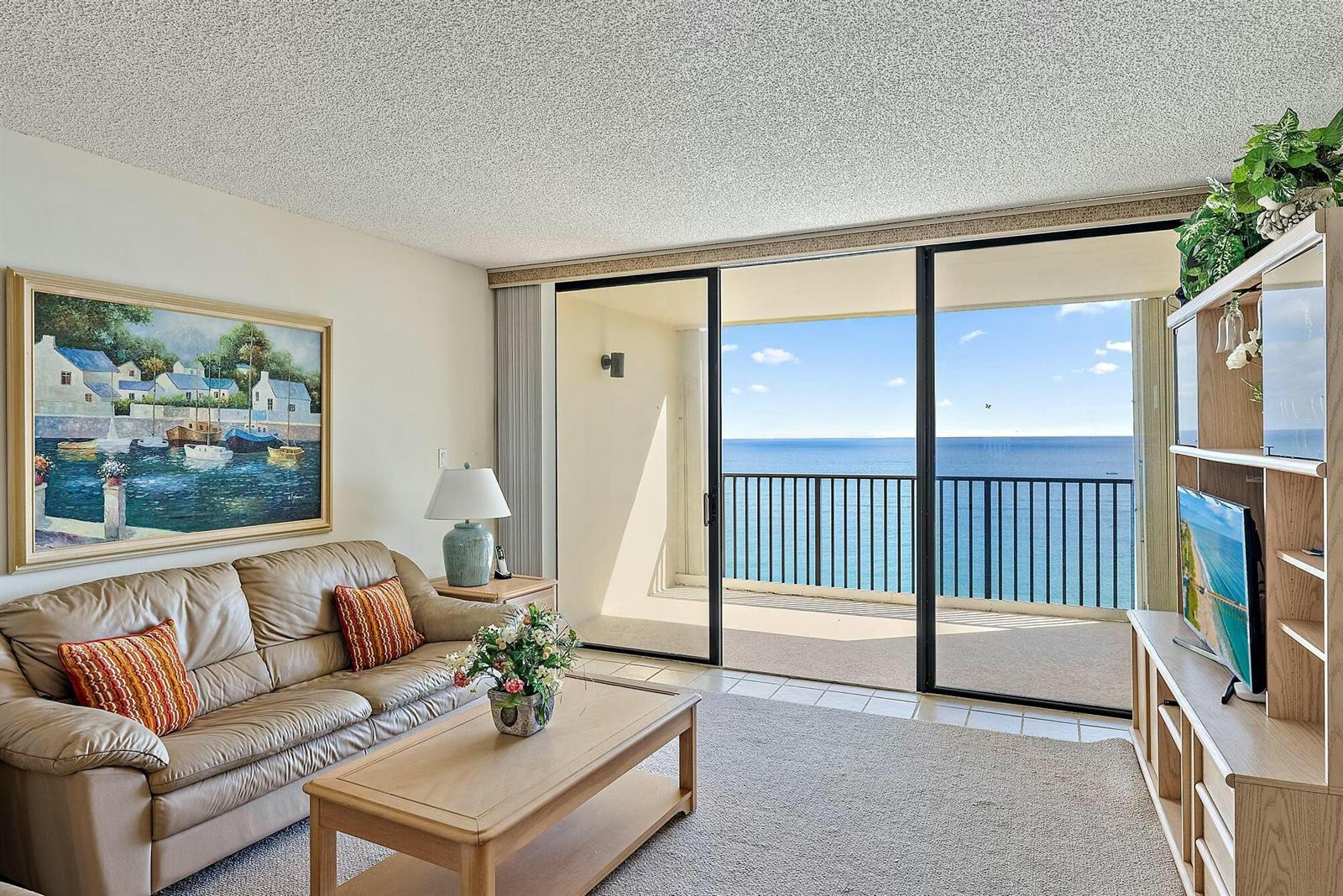 A living room features a leather sofa, a coffee table, and a balcony overlooking the ocean — 400 Ocean Trail Way # 1310, Jupiter FL 33477, JUPITER, FL