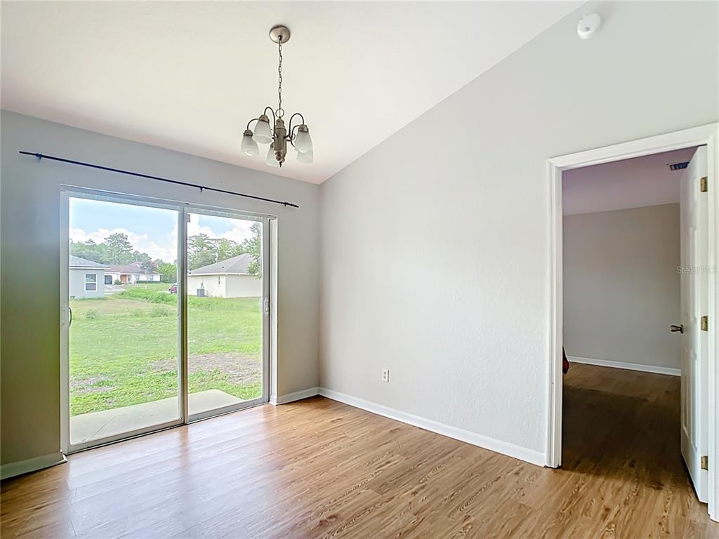 A dining room with wood-look flooring, a chandelier, and a sliding glass door to outside — 14939 SW 46TH CIRCLE, OCALA, FL