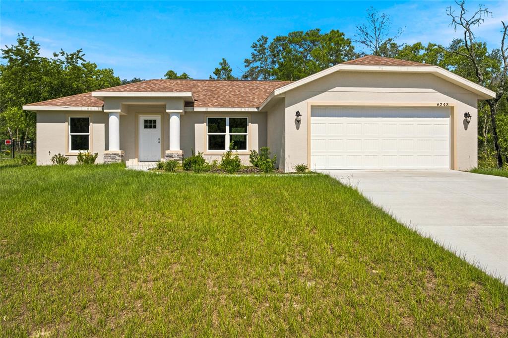 A single-story house with a beige stucco exterior, a two-car garage, and a covered entryway — 6243 N MATHESON DRIVE, CITRUS SPRINGS, FL