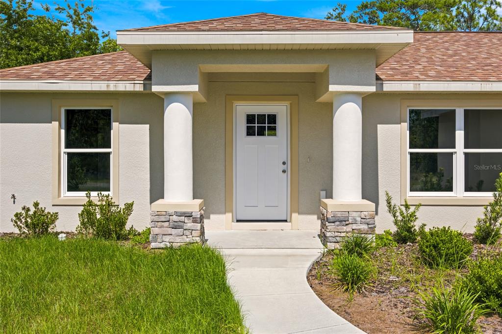 The exterior of a house features a white front door flanked by two stone-based columns — 6243 N MATHESON DRIVE, CITRUS SPRINGS, FL