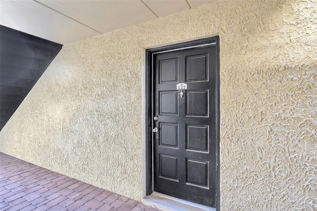 A black front door with the number 127 is set into a textured beige exterior wall — 5305 SAN SEBASTIAN COURT UNIT 127, TAMPA, FL