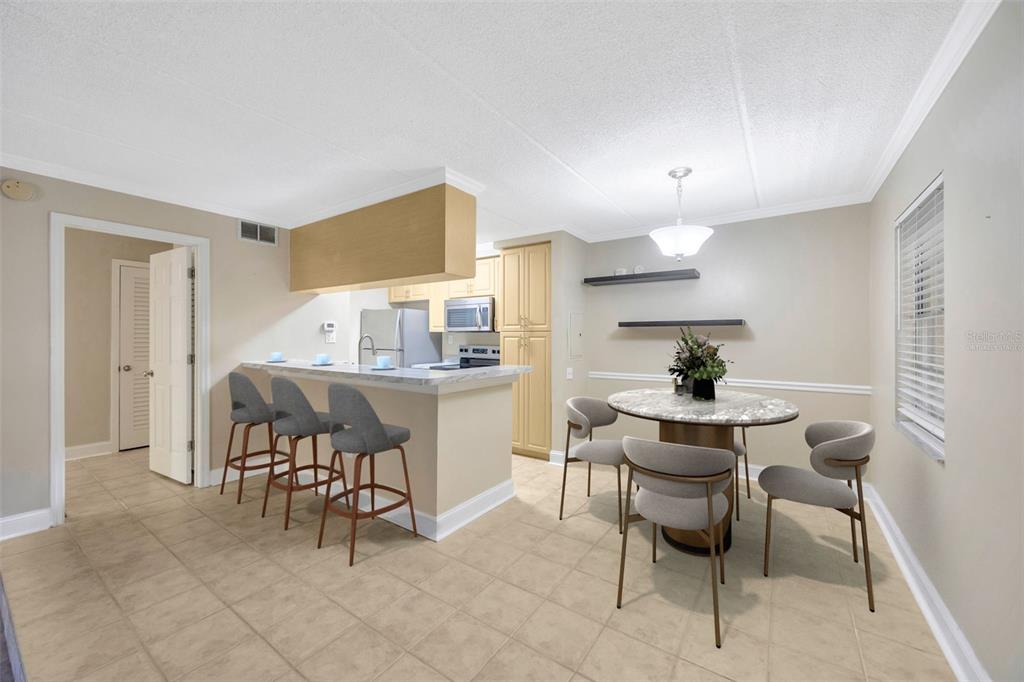A kitchen with a breakfast bar, dining area, light-colored cabinets, and tile flooring — 5305 SAN SEBASTIAN COURT UNIT 127, TAMPA, FL
