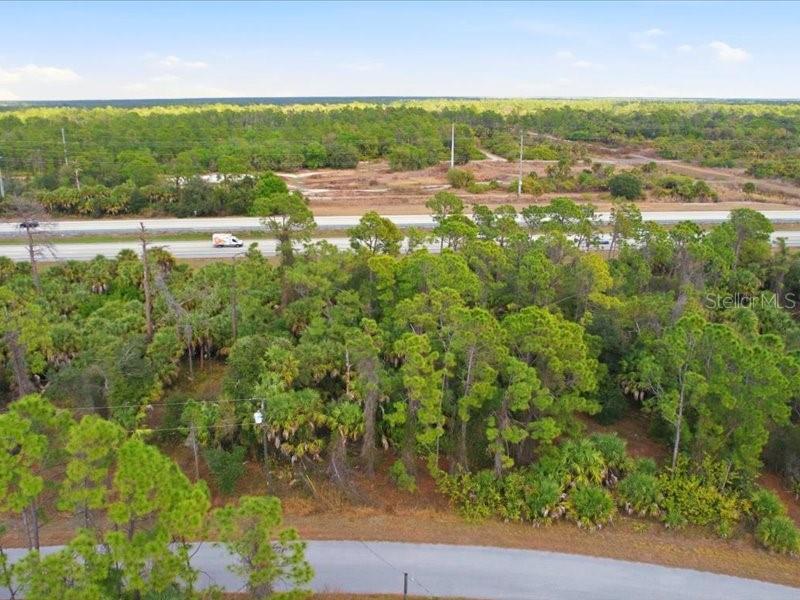 An aerial view shows a wooded lot adjacent to a highway — 1126207439 BARCELONA DRIVE, NORTH PORT, FL