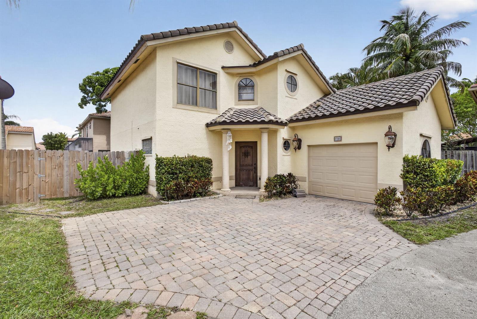 A two-story stucco house features a tiled roof, a paved driveway, and a wooden door — 1726 Shoreside Circle, Wellington FL 33414, WELLINGTON, FL