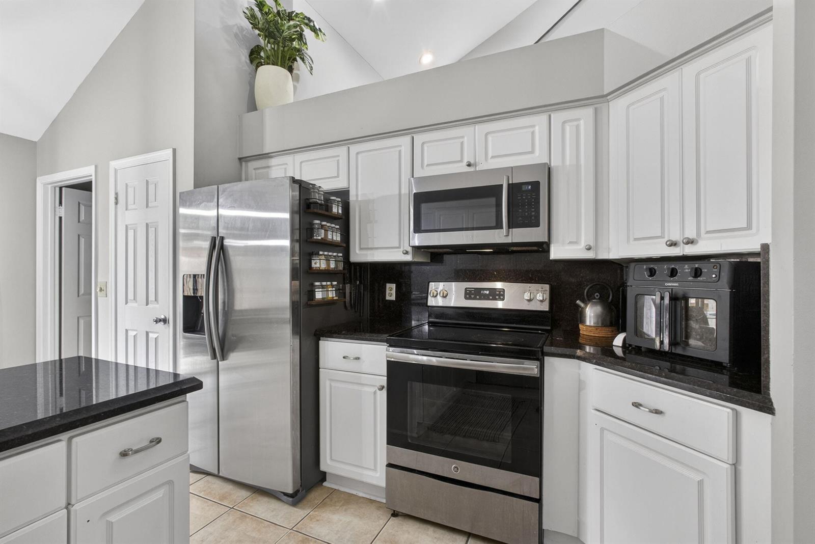 A kitchen features white cabinets, stainless steel appliances, and black granite countertops — 1726 Shoreside Circle, Wellington FL 33414, WELLINGTON, FL