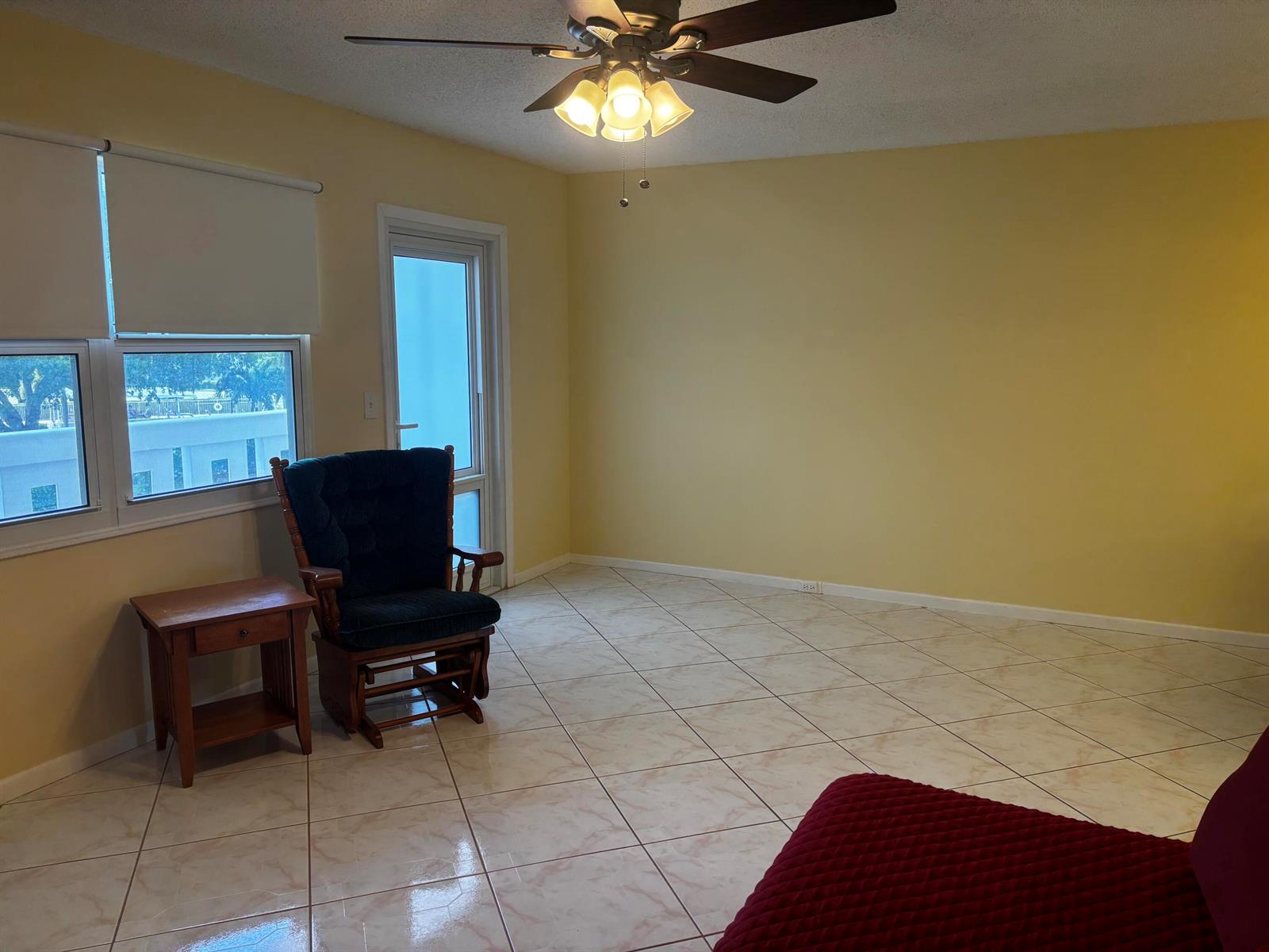 A living room with yellow walls, tile flooring, a ceiling fan, and a rocking chair — 309 Grantham A, Deerfield Beach FL 33442, DEERFIELD BEACH, FL