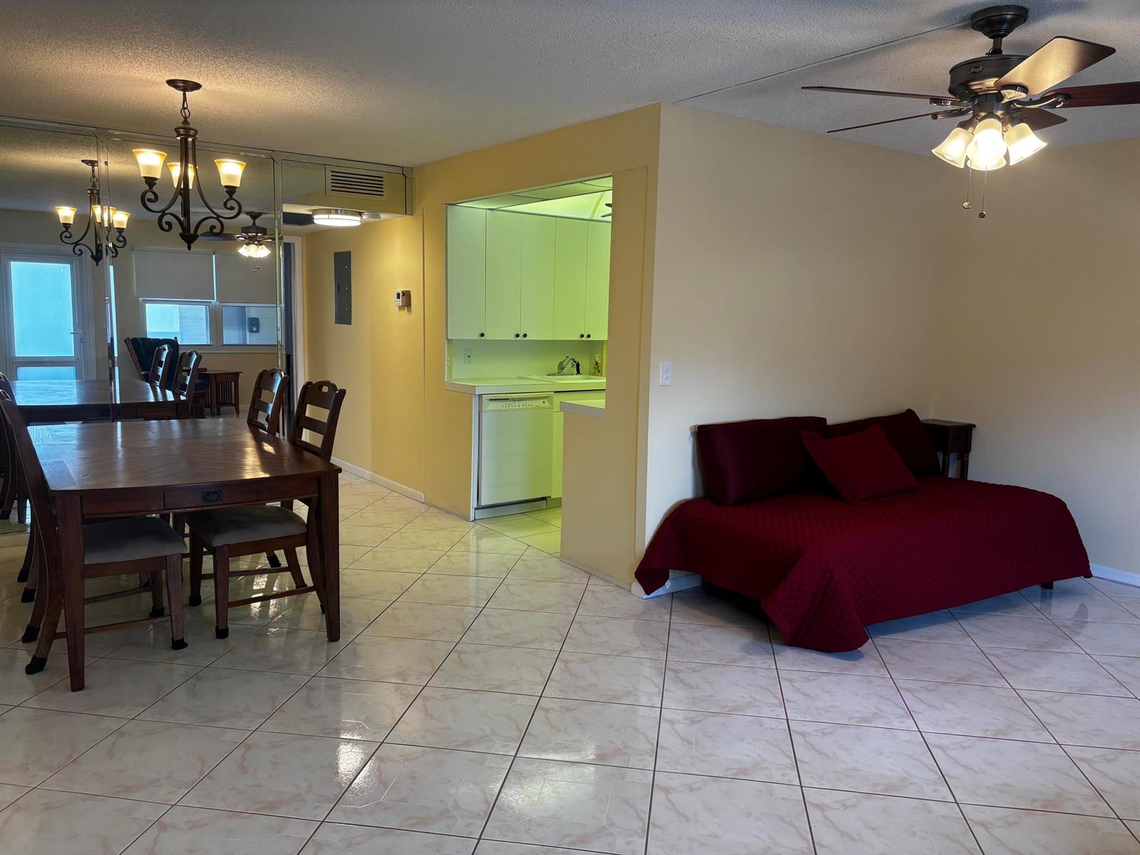 An open-concept living and dining area features tile floors, a kitchen pass-through, and a daybed — 309 Grantham A, Deerfield Beach FL 33442, DEERFIELD BEACH, FL