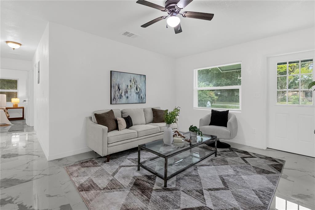 A living room features white walls, marble-look tile flooring, a sofa, and a glass coffee table — 107 FORD AVENUE, ALTAMONTE SPRINGS, FL