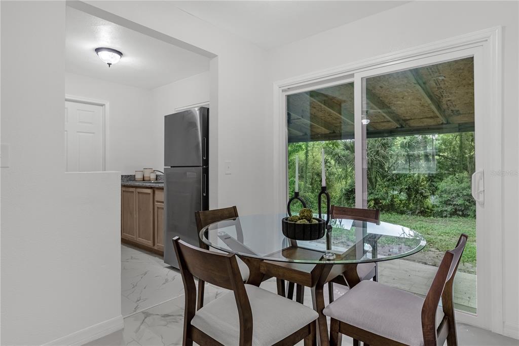 A dining area with a glass table and chairs overlooks a patio through sliding doors — 107 FORD AVENUE, ALTAMONTE SPRINGS, FL