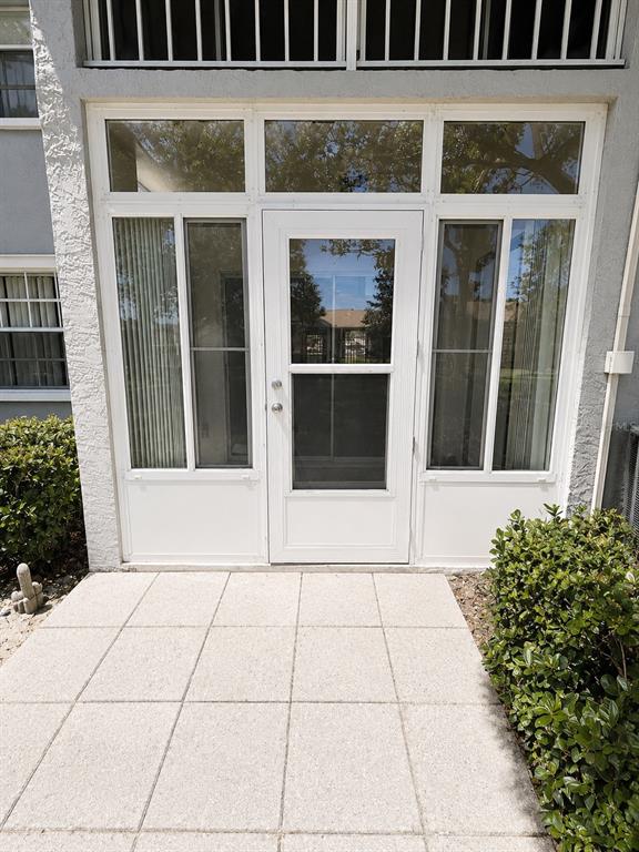 A white-framed glass storm door is centered between two large glass panels on a patio — 1420 OAK HILL DRIVE UNIT 102, DUNEDIN, FL