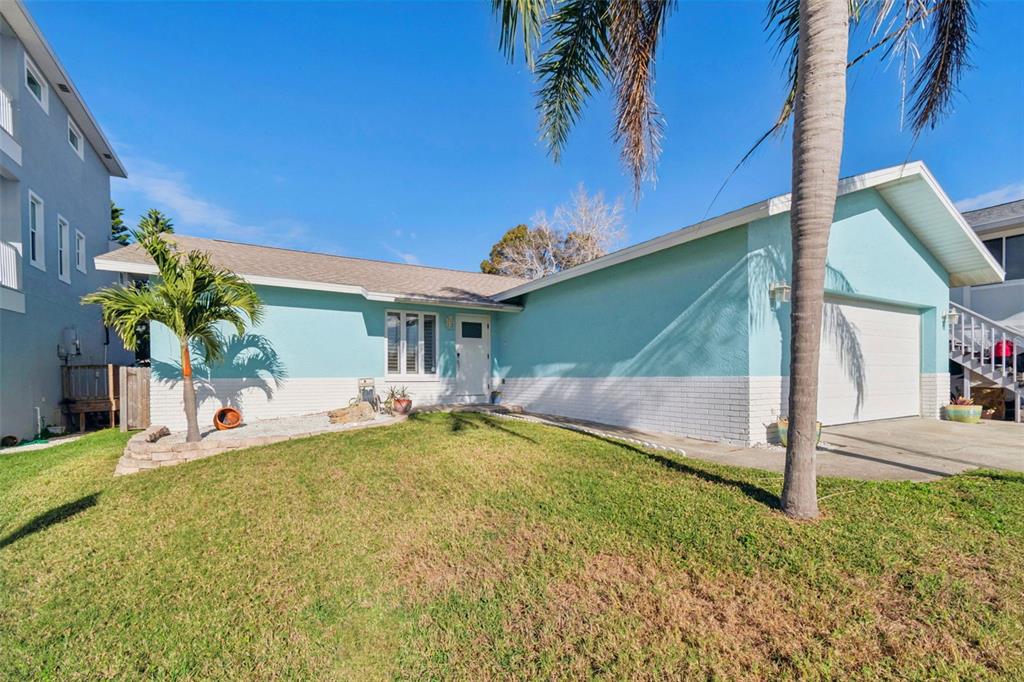 A light blue, single-story house with a white brick base and a two-car garage — 216 176TH AVENUE E, REDINGTON SHORES, FL